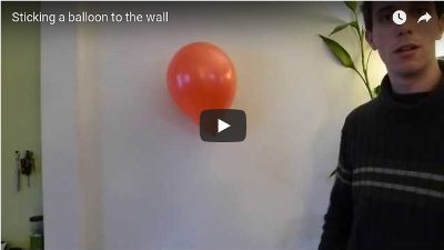 A charged balloon sticks to a wall.